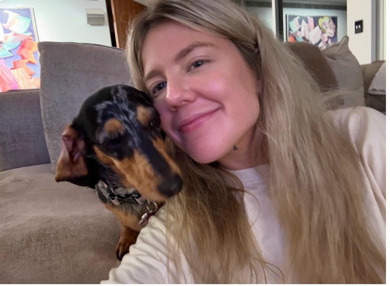 Sitter cuddling a dachshund on the couch of a Brisbane home, mid-afternoon and half asleep